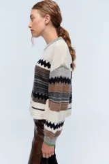 Sweater de lana merino color crudo con diseño geométrico, cuello redondo con detalle de color verde y lentejuelas delicadas.