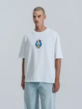 Remera blanca de manga corta con cuello redondo y calce oversize. Presenta un estampado frontal de Mickey Mouse vestido de chef.