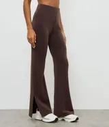 Pantalón deportivo de corte flare, color marrón, con cintura elástica y diseño liso. Presenta una abertura lateral en el bajo.