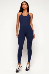 Monopieza deportiva color azul marino, de corte largo, con cuello halter y espalda descubierta.
