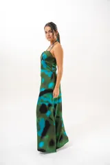 Vestido largo con estampado abstracto en tonos verdes, azules y negros. Presenta tirantes finos y cuello halter cruzado con detalle de abertura en el pecho.
