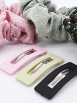 Set de seis accesorios para el pelo que incluye tres coleros de tela con textura arrugada en colores rosa, verde y negro con estampado floral, y tres broches rectangulares con clip en colores rosa, verde y negro.