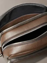 Cartera bandolera Calvin Klein de piel sintética texturizada, color marrón oscuro, con silueta estructurada y correa ajustable. Presenta un bolsillo exterior frontal y un compartimento principal con cierre de cremallera.