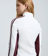 Campera deportiva de corte ajustado, color blanco con paneles laterales y detalles en mangas color bordó. Presenta cierre frontal completo, cuello alto y estampa con lettering 'Oregon' en el pecho.