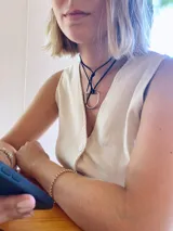 Gargantilla con cordón negro y dije metálico plateado en forma de estribo.