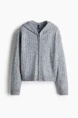 Saco corto de punto trenzado con capucha, cierre frontal y hombros caídos. Presenta puños y bajo en punto acanalado.