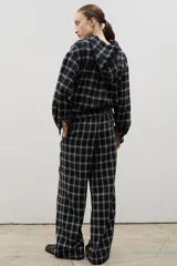 Pantalón de corte amplio y tiro medio-alto, confeccionado en tejido liviano con estampado a cuadros. Presenta cintura elastizada con lazo regulable y bolsillos laterales.