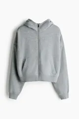 Campera canguro de felpa color gris, de corte holgado con hombros caídos, capucha forrada, cierre frontal y bolsillos tipo parche en la parte delantera. Presenta puños y dobladillo en punto acanalado.