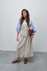 Chaleco de calce entallado color beige, de estilo cruzado con doble botonadura y escote redondo.
