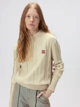 Sweater de punto con diseño de rayas verticales en tonos negro y gris oscuro. Presenta cuello alto tipo polera, mangas largas con puños ajustados y ruedo elástico. Incluye un pequeño bordado en color rojo en el pecho.