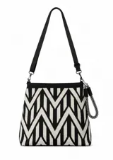 Cartera tipo bandolera con diseño geométrico en zigzag blanco y negro. Cuenta con una correa larga ajustable y desmontable, y un asa de mano corta tipo cuerda trenzada.