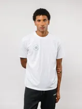 Remera de manga corta color blanco con cuello redondo. Presenta un pequeño logo circular de Umbro estampado en el pecho con la leyenda 'Born to Play'.