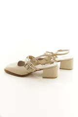 Zapatos tipo Mary Jane de charol color negro, con taco bloque, talón descubierto y doble tira frontal con hebillas metálicas.