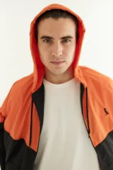 Campera de nylon impermeable con capucha, color naranja en la parte superior y negro en la parte inferior.
