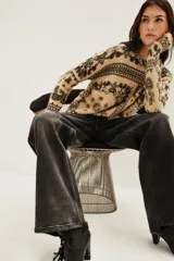 Sweater de punto con diseño estampado estilo paisley en tonos beige y negro, de cuello redondo y manga larga.