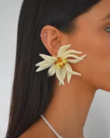 Aros colgantes con forma de flor de pétalos color crema y centro con cuentas amarillas y marrones.