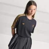 Camiseta de fútbol Adidas del Manchester United, modelo Terrace Icons. Diseño negro con sutiles rayas verticales moradas, franjas amarillas en los hombros y detalles bordados en dorado, incluyendo el trébol de Adidas y el escudo clásico del club.
