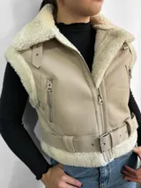 Chaleco color beige con interior de piel sintética blanca, cierre frontal con cremallera y cinturón ajustable en la cintura.