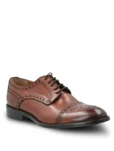 Zapato de vestir tipo Oxford con diseño brogue, confeccionado en cuero vacuno de color marrón. Presenta cierre mediante cordones, puntera redondeada con detalle de perforaciones decorativas y suela mixta de cuero y goma.