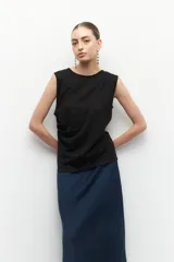 Top sin mangas color beige, de cuello redondo y corte ajustado. Presenta frunces en los laterales.