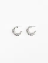 Aros tipo argolla gruesos de color plateado, con diseño geométrico de textura rayada y cierre de perno.