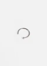 Piercing de titanio plateado, con forma de aro abierto y extremo con tope plano.