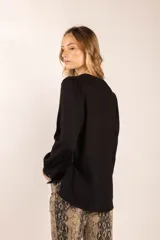 Blusa color crema de lino y viscosa, con escote en V, mangas largas abullonadas y puños con botón.