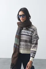 Sweater de punto con diseño jacquard de inspiración nórdica, cuello redondo y mangas largas. Presenta un patrón geométrico en tonos tierra, azul y blanco, con puños y ruedo acanalados.