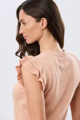 Remera tejida de algodón color beige, de corte clásico con cuello redondo y mangas cortas decoradas con volados fruncidos.