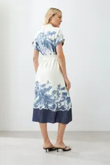 Vestido midi color blanco con estampado de paisley en azul y cinturón de lazo.