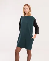 Vestido corto negro con mangas 3/4 verdes, cuello bote y bolsillos laterales.