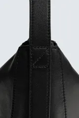 Bolso de hombro de diseño minimalista confeccionado en piel de alta calidad. Cuenta con un compartimento principal con cierre de cremallera, interior con bolsillos organizadores y asa de hombro fija. Incluye un detalle de llavero colgante.
