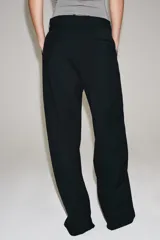 Pantalón de lana negro de tiro medio con trabillas en la cintura, bolsillos laterales ocultos y pierna ancha.