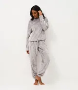 Conjunto de pijama largo de dos piezas confeccionado en tejido fleece suave y abrigado. Incluye una blusa de manga larga con cuello redondo y ajuste en la cintura, y un pantalón con cintura elástica. Ambas prendas presentan una textura grabada con diseño de gatitos.