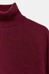 Jersey de punto confeccionado en lana, con cuello subido y manga larga.