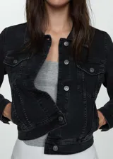 Chaqueta de denim negro estilo vaquero, con cuello clásico, cierre frontal de botones metálicos, bolsillos con solapa en el pecho y bolsillos laterales.