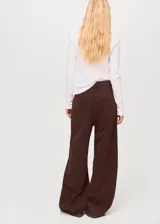 Pantalón de jean estilo wide leg color marrón chocolate, con tiro medio, cinco bolsillos, cierre frontal con cremallera y botón, y detalle de costuras en la cadera.