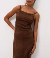 Vestido midi de gamuza sintética color marrón, con diseño de bordado de follaje en relieve. Presenta escote recto, tirantes finos regulables, ajuste al cuerpo, espalda con lastex y abertura frontal en la falda.