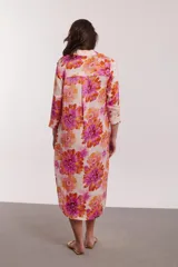Vestido camisero midi con estampado floral en tonos naranja, rosa y fucsia. Tiene cuello camisero, mangas 3/4 y aberturas laterales.