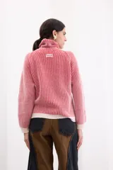 Sweater de punto con cuello tortuga y diseño a rayas verticales en color rojo y blanco. Presenta mangas largas con puños y ruedo en tejido liso de color crema, con un sutil acabado brillante.