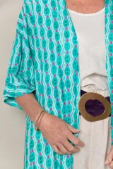 Túnica larga estampada en tonos turquesa, blanco y fucsia, con mangas cortas, calce holgado, tajos laterales y detalle de guarda en el ruedo.