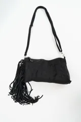 Cartera bandolera de gamuza negra con flecos largos en uno de sus laterales. Cuenta con cierre superior y correa larga ajustable.