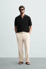 Polo de manga corta, color azul medio, tejido en punto perlado con cuello solapa y cierre frontal de cremallera.