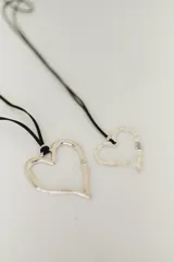 Collar con dije de corazón plateado y cordón negro.