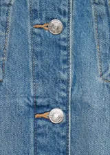 Chaqueta de jean con diseño oversize, cuello camisero, cierre frontal con botones metálicos, dos bolsillos de parche con solapa en el pecho y dos bolsillos laterales de ribete.