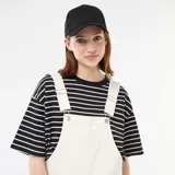 Enterito corto oversize de color blanco, con diseño de peto, tirantes ajustables con hebilla metálica y bolsillos frontales.