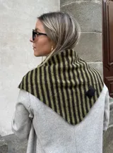 Bufanda triangular de tejido de punto con diseño de rayas verticales en tonos verde oliva y marrón oscuro. Presenta una etiqueta de cuero sintético negra en uno de sus extremos.