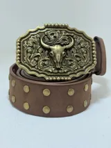 Cinto marrón con tachas doradas y hebilla rectangular dorada con diseño de calavera de vaca y ornamentos florales.
