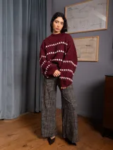 Buzo corto de tejido de punto en color negro, con diseño de textura en relieve y líneas horizontales blancas. Presenta cuello redondo y mangas largas con puños ajustados.