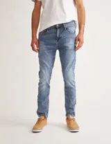 Pantalón jean celeste de corte slim fit, con arrugas en la parte superior de las piernas.